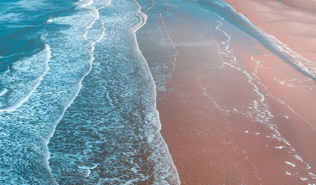 Нежные белые волны омывают песчаный берег океана 