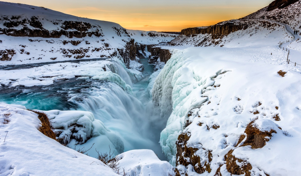 Заледеневший водопад у покрытых снегом берегов, Исландия