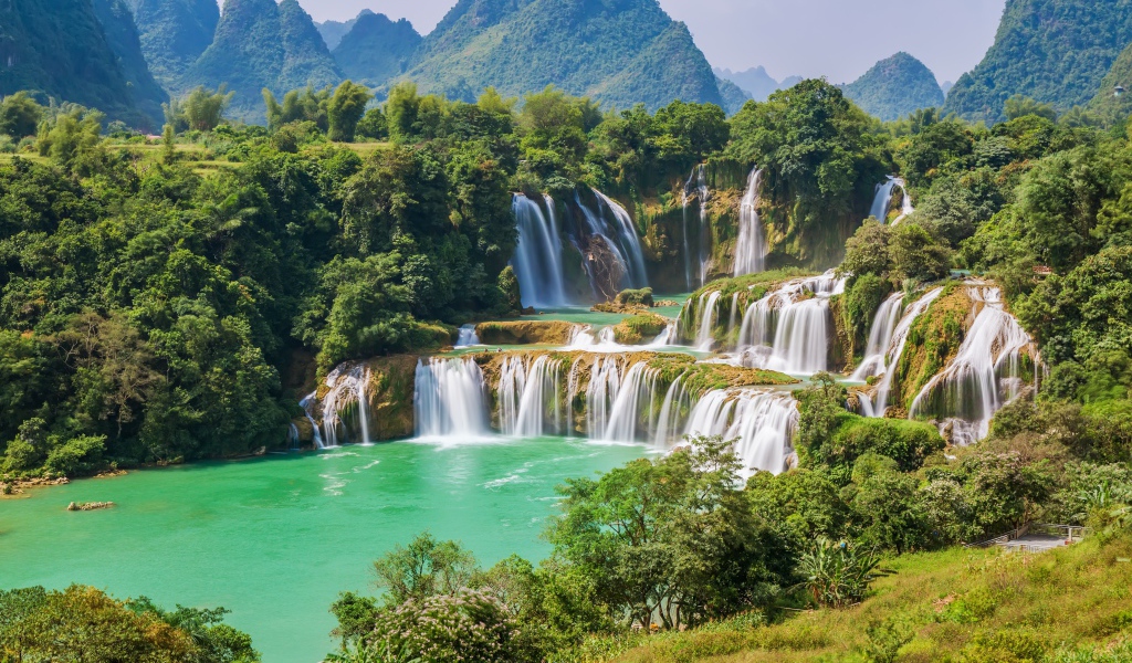 Водопад стекает с гор на фоне зеленой природы