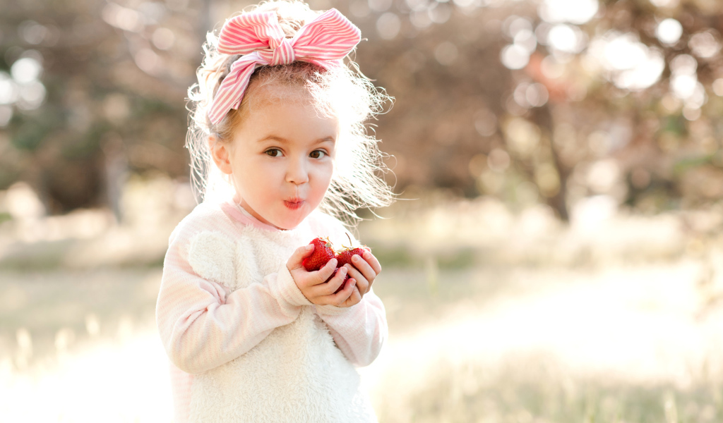 Милая маленькая девочка ест клубнику