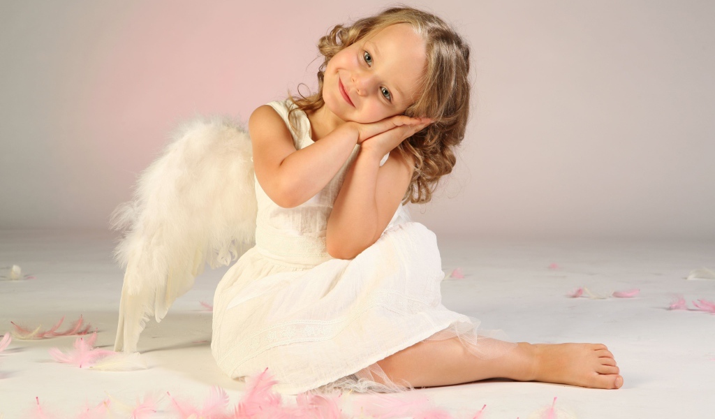 Милая маленькая девочка в белом платье с крыльями ангела
