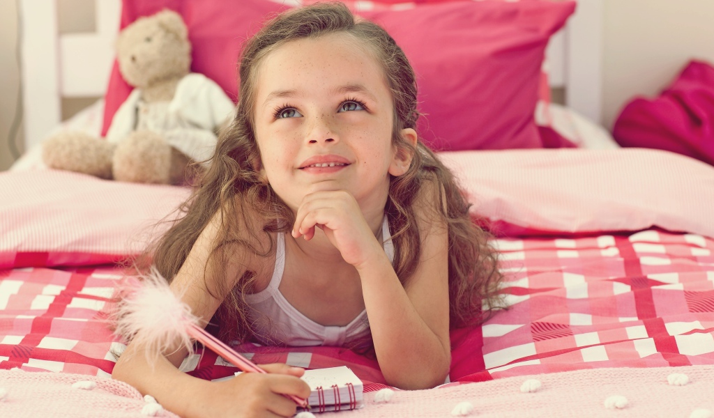 Замечтавшаяся маленькая девочка лежит на кровати