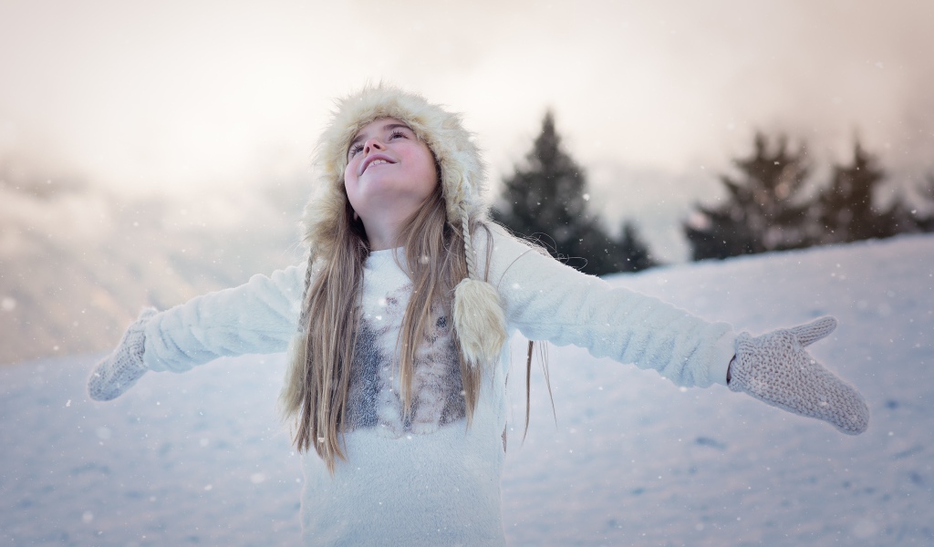 Девочка в белой шапке радуется снегу