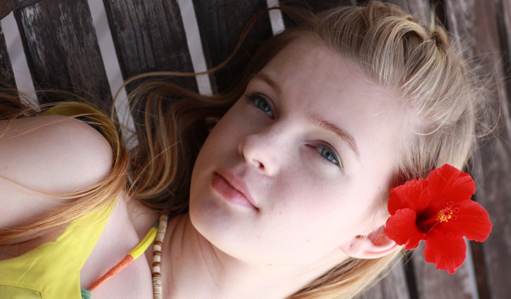 Девочка с красным цветком гибискуса в волосах