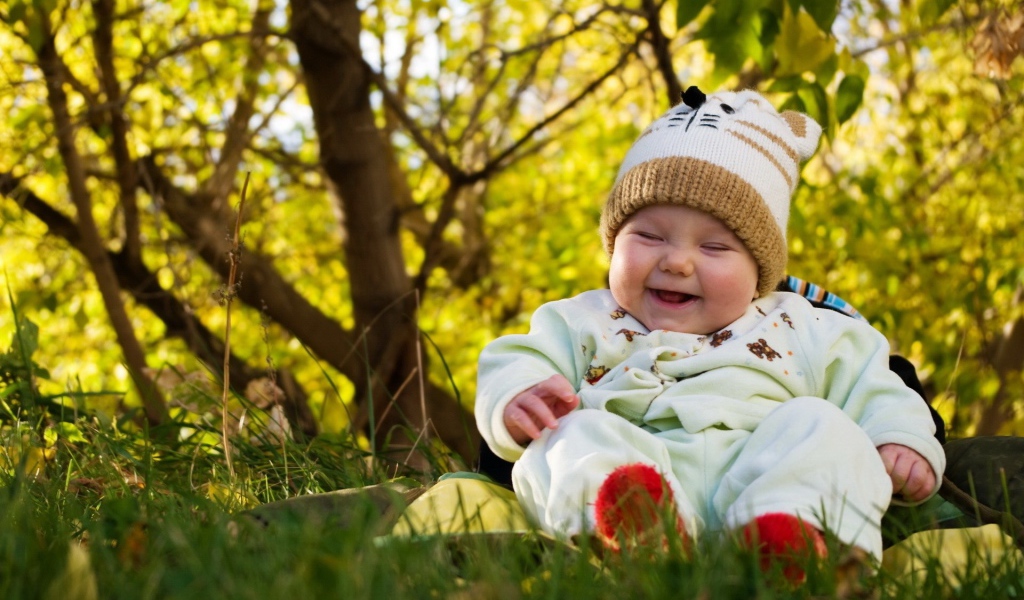 Смеющийся грудной ребенок сидит на траве