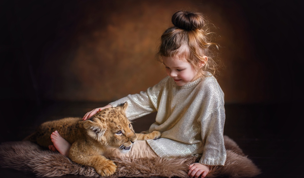 Маленькая девочка гладит маленького львенка