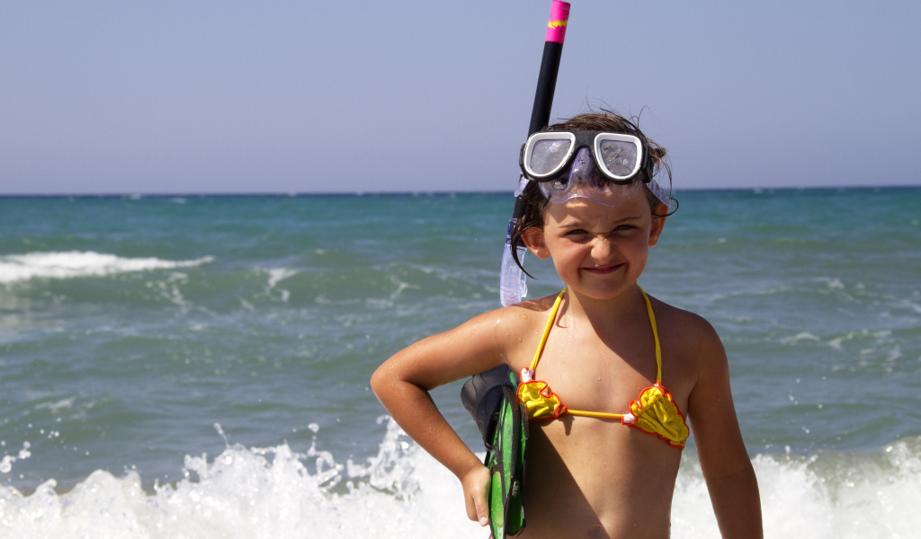 Маленькая девочка в очках и с ластами на море