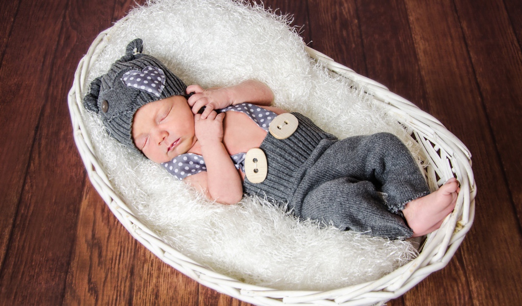 Спящий младенец в сером костюме в белой корзине