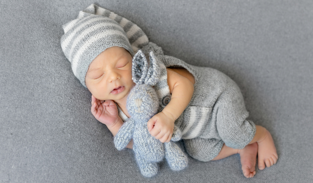 Спящий младенец с серым вязаным зайцем