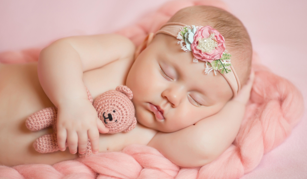 Спящая маленькая девочка с вязаным медвежонком в руке