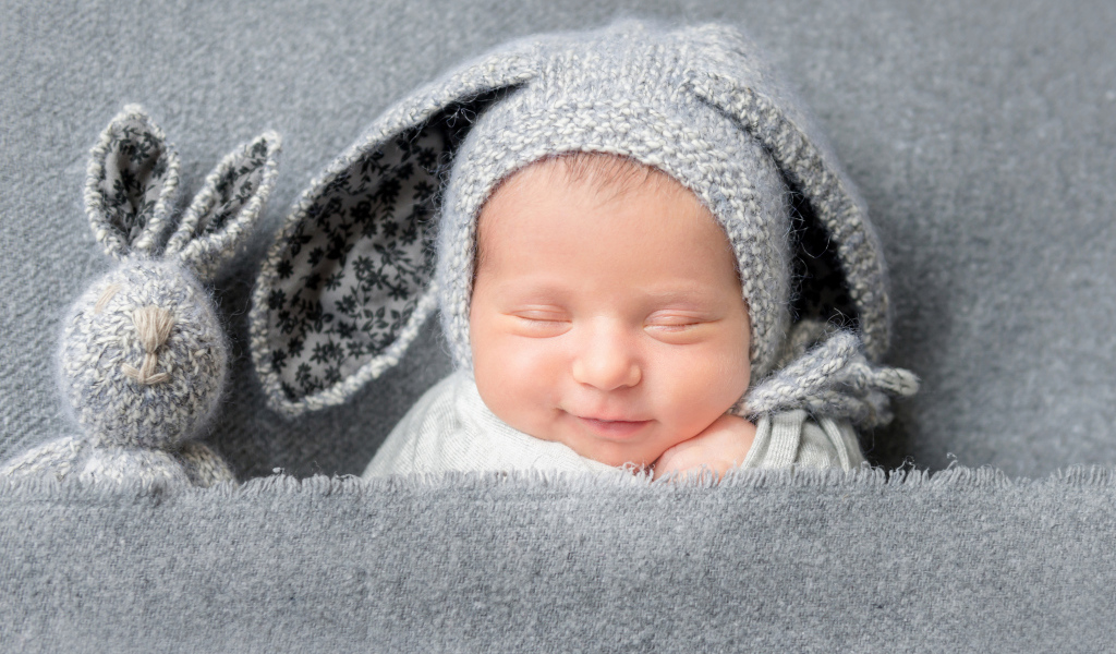 Маленький грудной ребенок в серой шапке с ушками