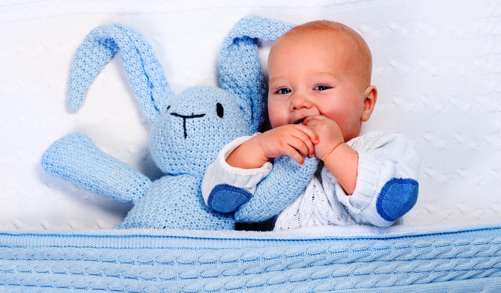 Маленький грудной ребенок грызет мягкую игрушку 