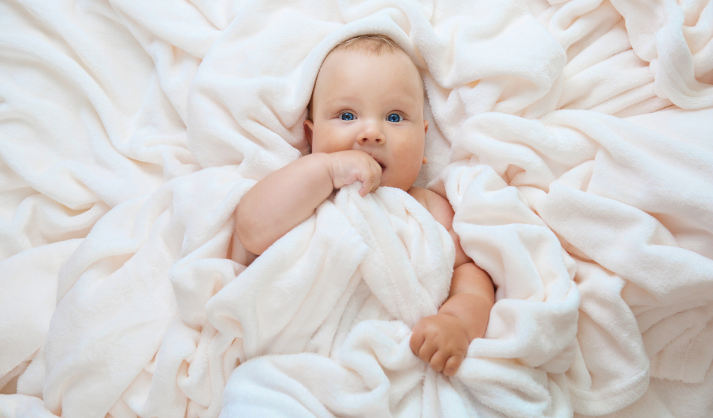 Маленький голубоглазый ребенок в покрывале 