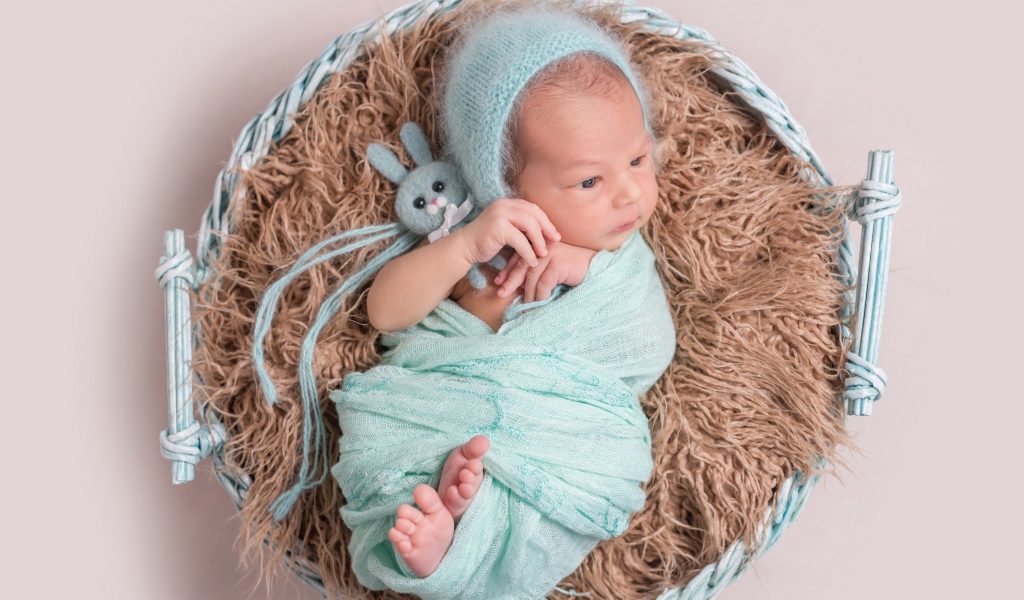 Маленький ребенок в корзине на сером фоне