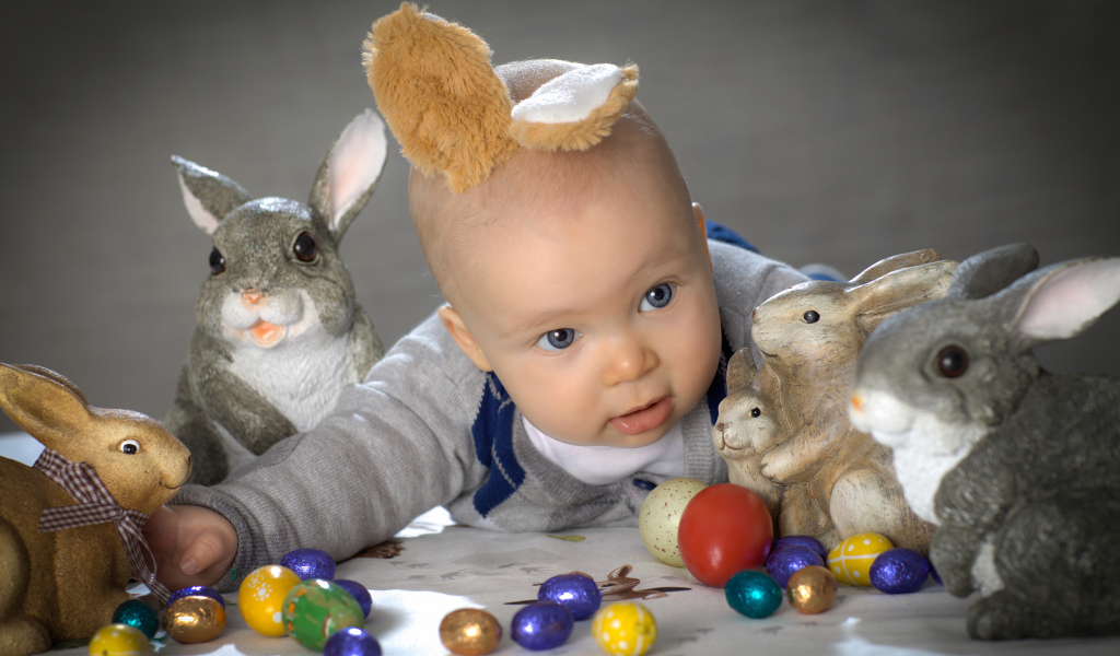 Маленький ребенок с пасхальными кроликами и яйцами
