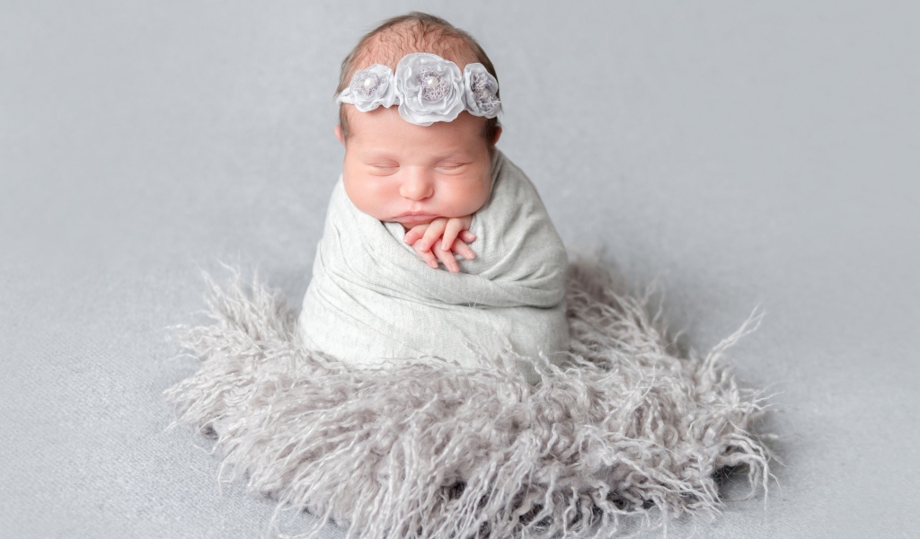 Маленький спящий младенец на сером фоне