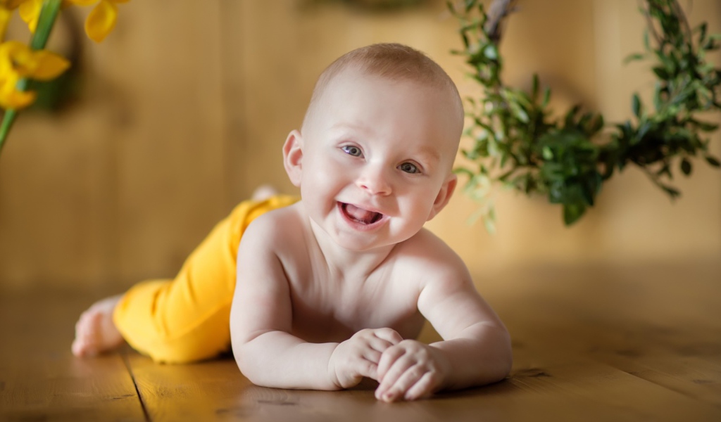 Улыбающийся малыш лежит на деревянном полу