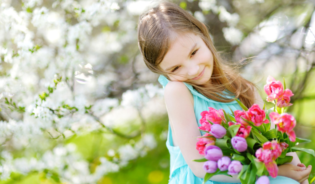 Красивая маленькая девочка с букетом тюльпанов весной