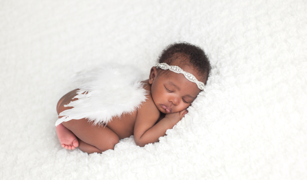 Темнокожий младенец спит с крыльями ангела