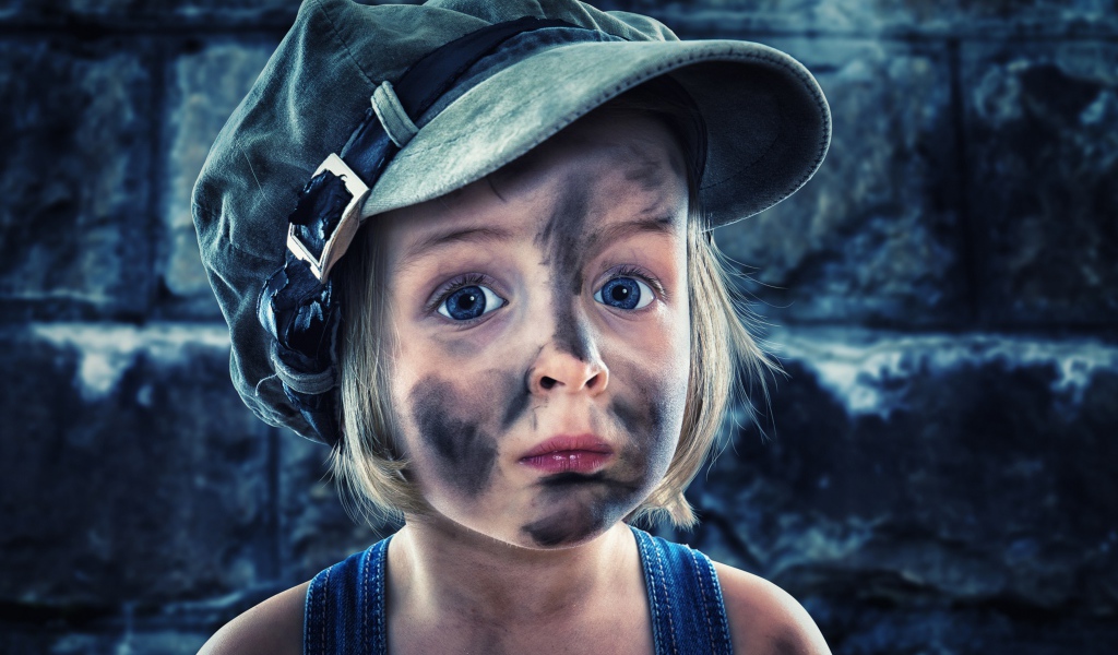 Смешная девочка в кепке с грязным лицом