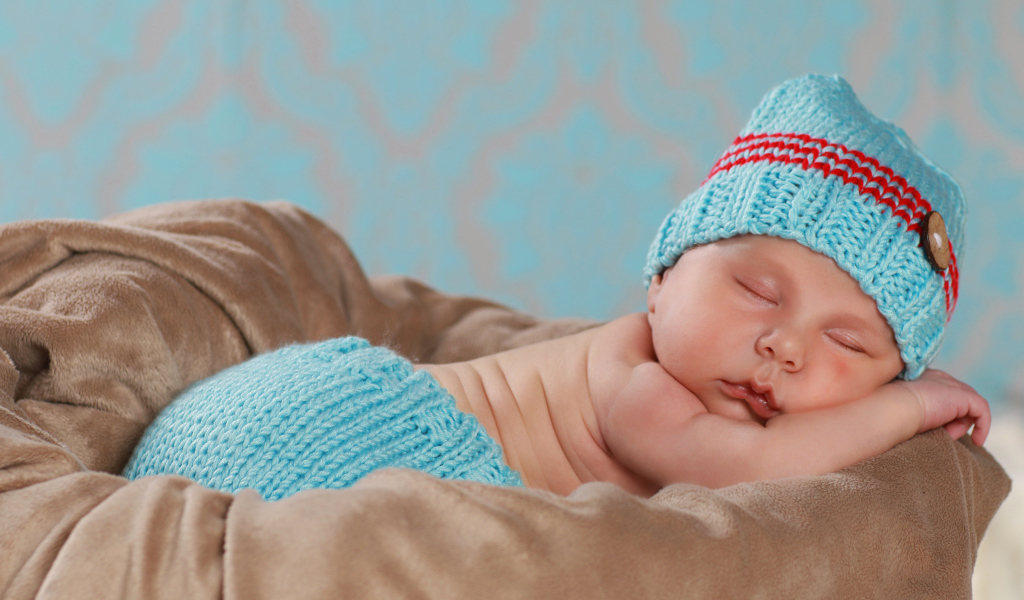 Забавный спящий младенец в голубом вязаном костюме 