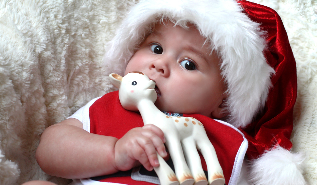 Маленький ребенок в новогодней шапке с игрушкой в руке