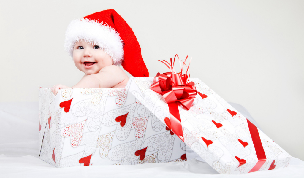 Маленький ребенок в новогоднем костюме в коробке для подарка на сером фоне
