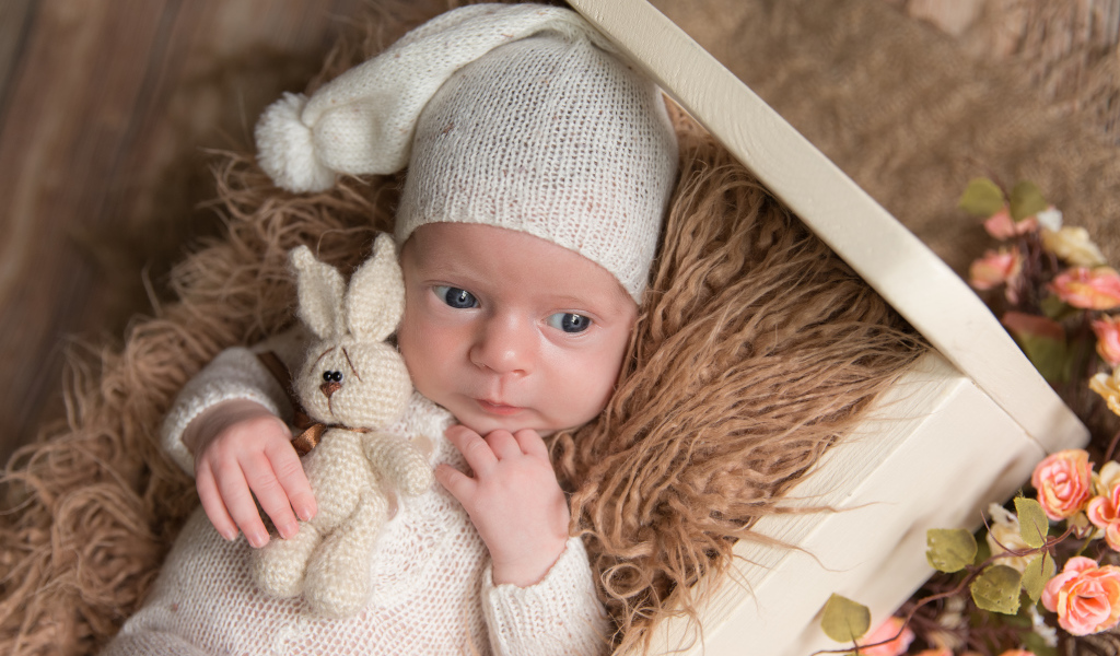 Маленький ребенок в вязанном костюме с зайчиком