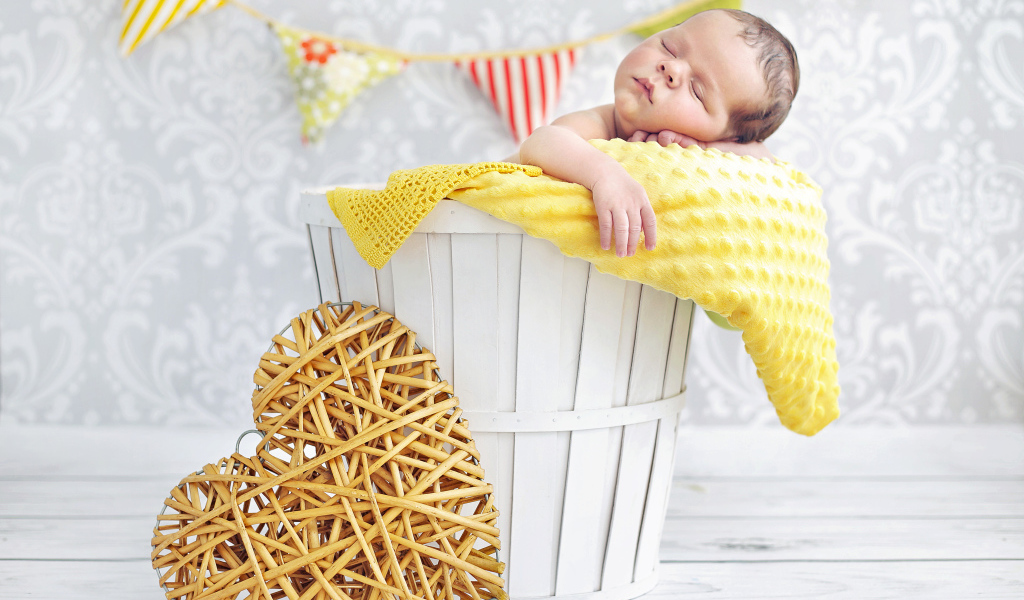 Маленький ребенок спит в корзине с плетеным сердцем