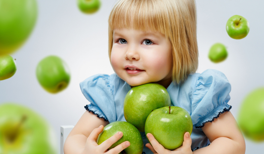 Маленькая девочка блондинка с зелеными яблоками
