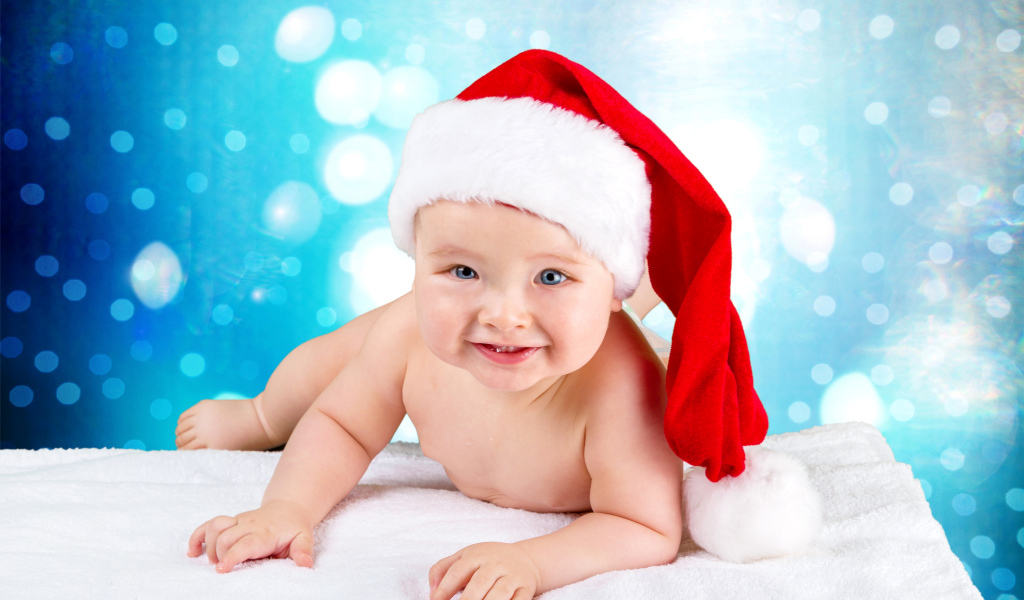 Маленький голубоглазый ребенок в красном новогоднем колпаке