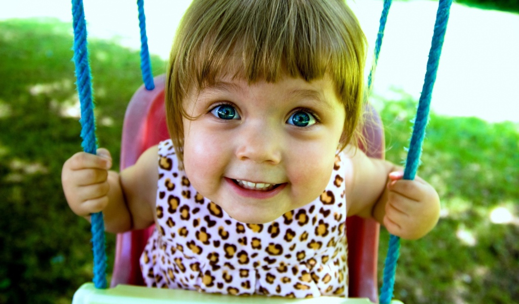 Маленькая голубоглазая девочка на качели