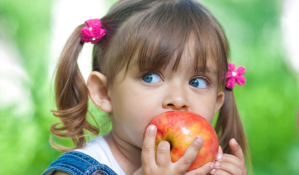 Маленькая голубоглазая девочка с большим яблоком