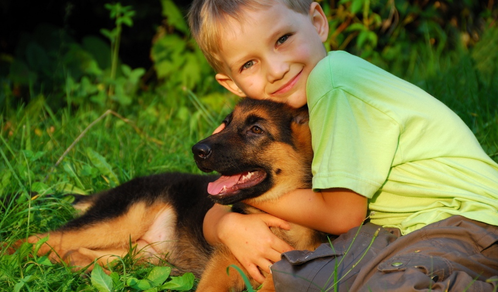 Маленький мальчик обнимает щенка немецкой овчарки