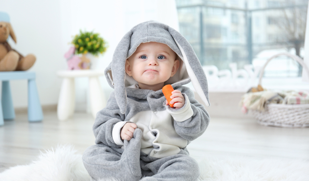 Маленький мальчик в костюме зайчика с морковкой в руке