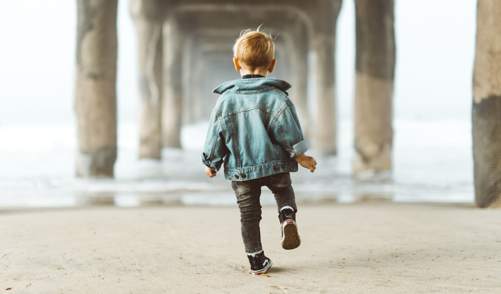 Маленький мальчик в джинсовой куртке спиной