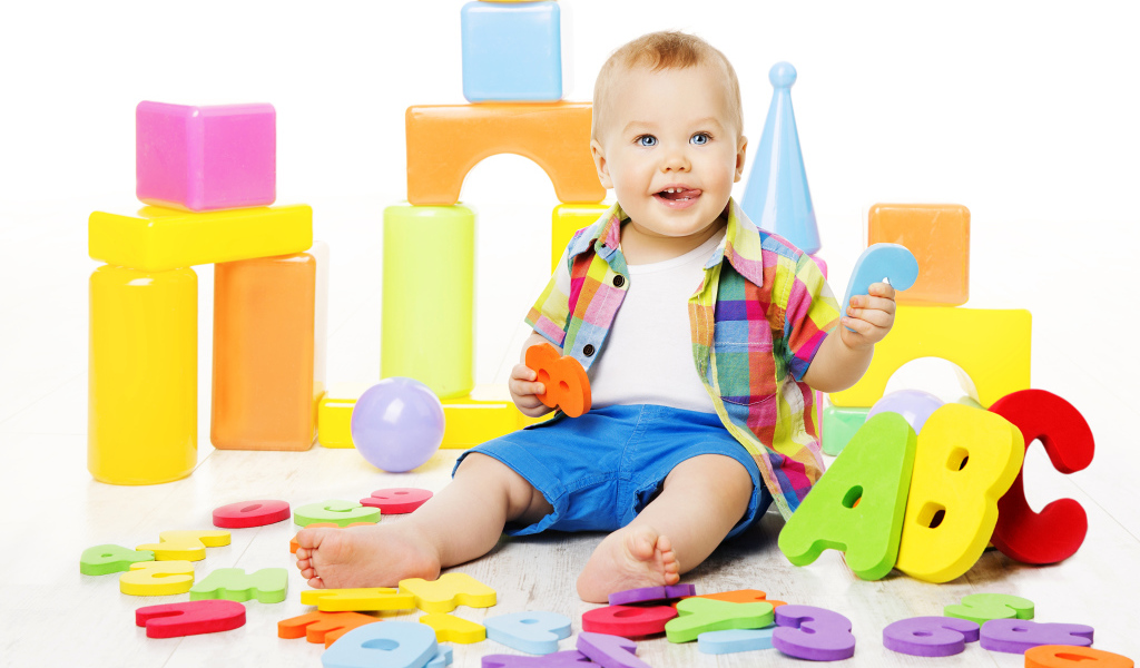 Маленький мальчик играет с разноцветными игрушками 