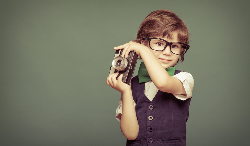 Маленький мальчик в очках с фотоаппаратом