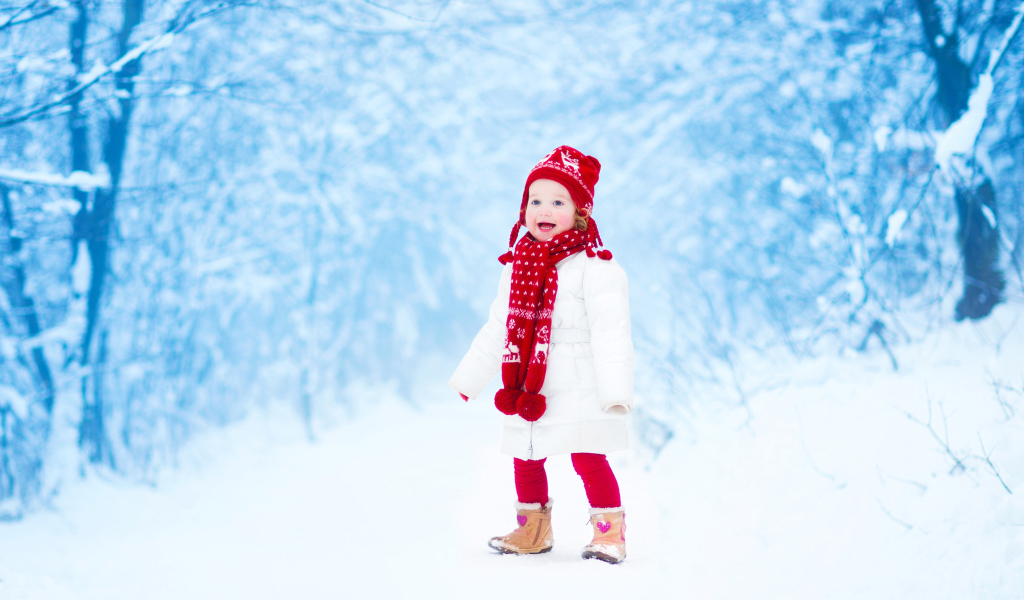 Маленькая веселая девочка в зимнем лесу