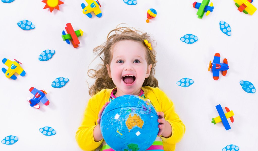 Маленькая веселая девочка с глобусом в руках 