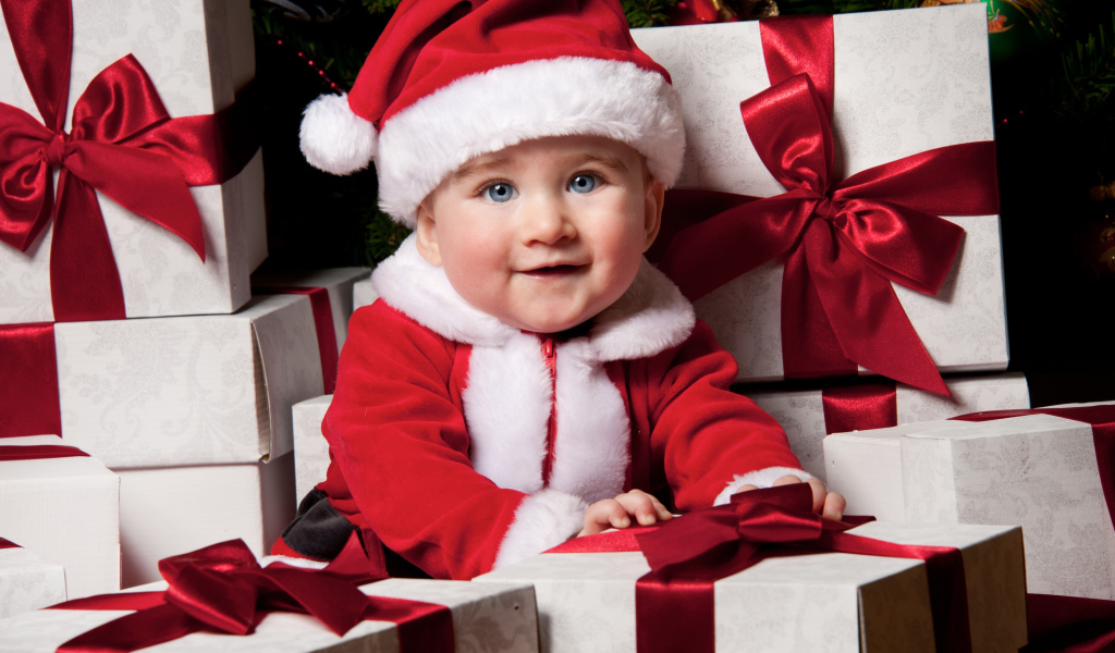 Маленький забавный голубоглазый ребенок в костюме Санты сидит на подарках