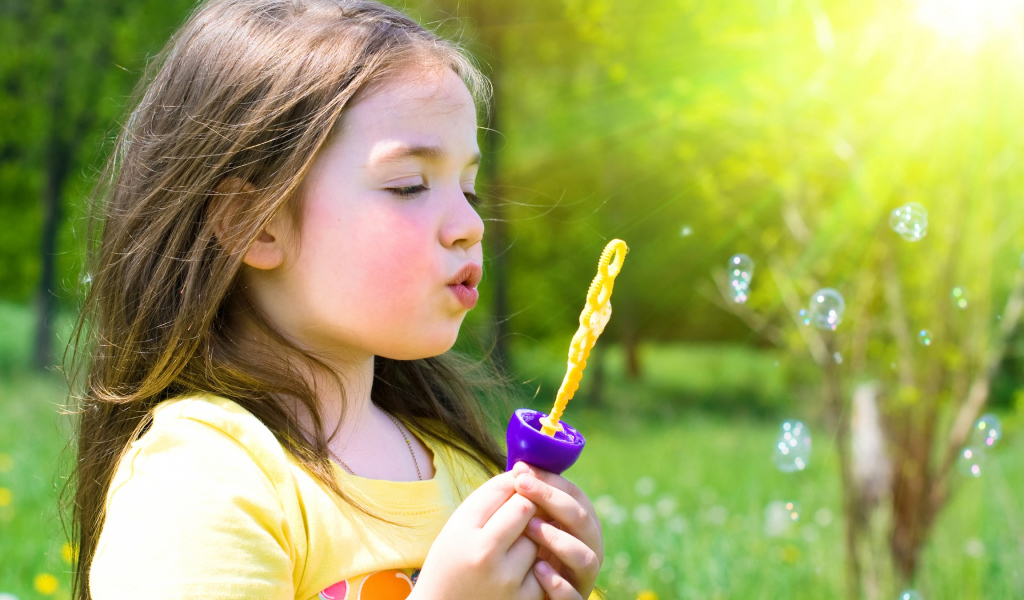 Маленькая девочка пускает мыльные пузыри