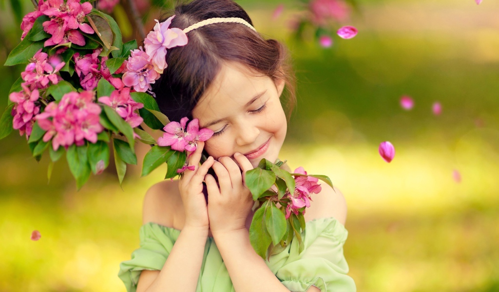 Маленькая девочка обнимает ветку с розовыми цветами