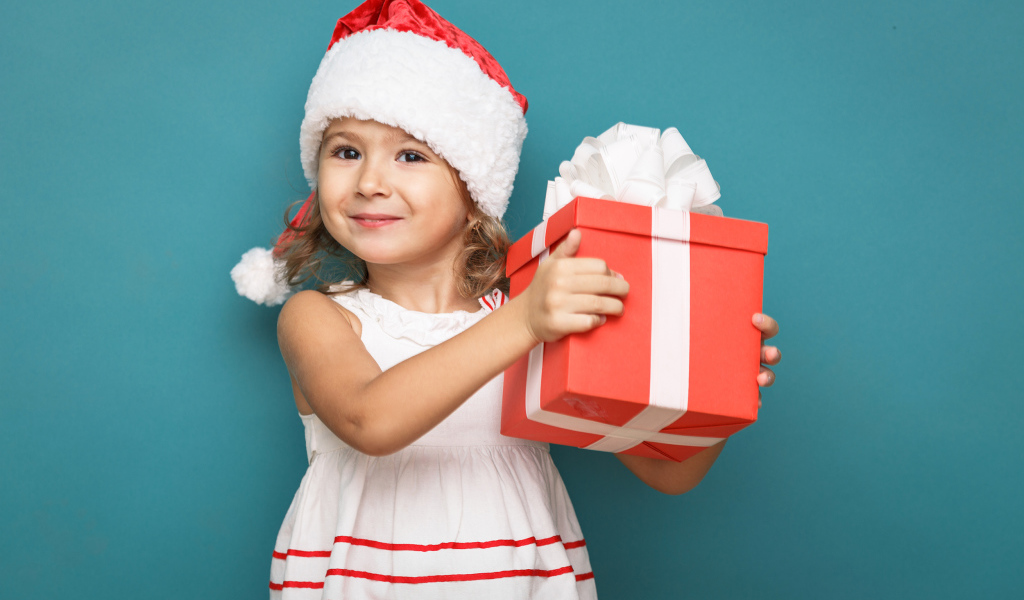 Маленькая девочка в новогоднем костюме с подарком на голубом фоне