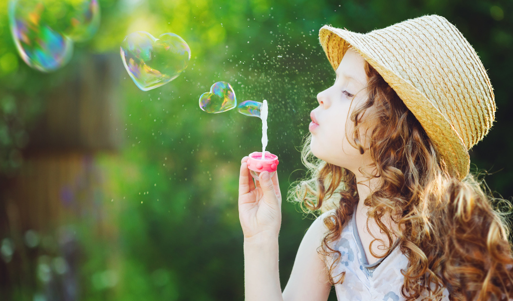 Маленькая девочка в шляпе с мыльными пузырями