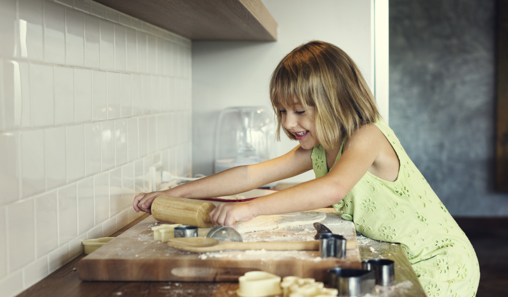 Маленькая девочка на кухне готовит печенье