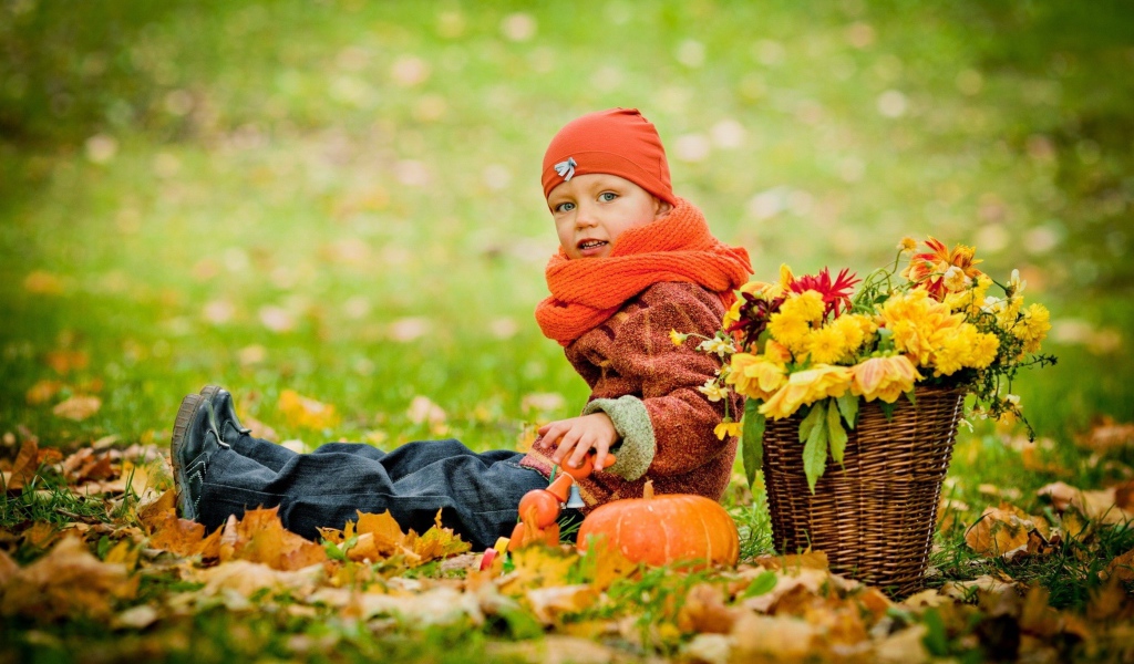 Маленькая девочка сидит на траве с корзиной цветов осенью