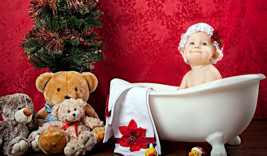 Маленькая девочка сидит в белой ванне у елки с игрушками