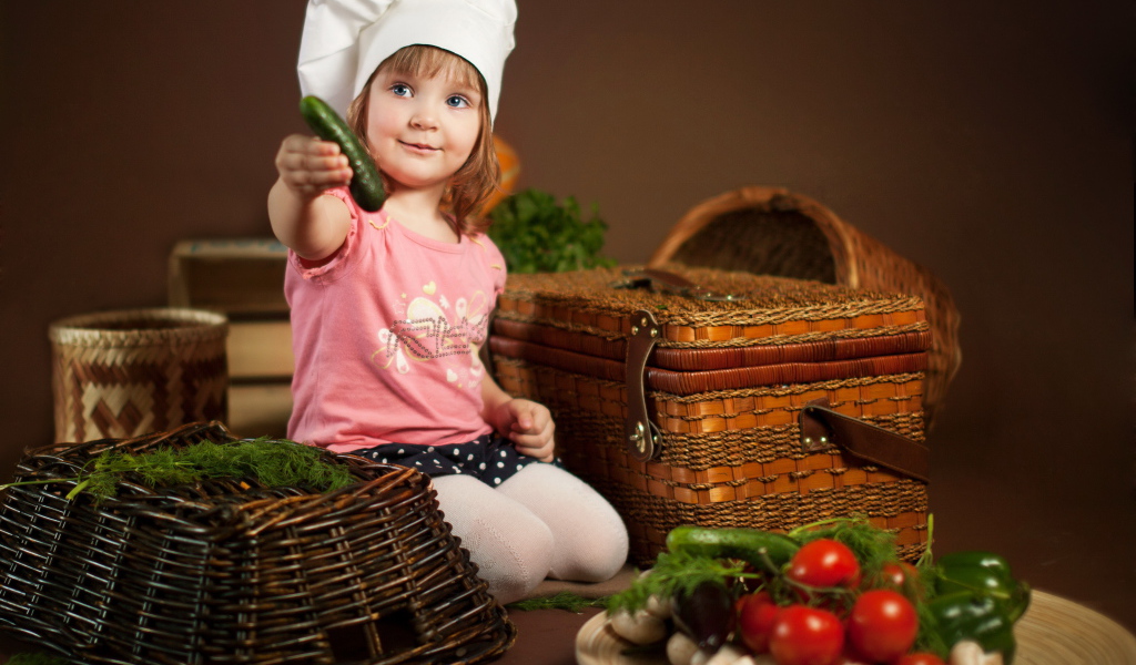 Маленькая девочка сидит на столе с корзинами и овощами