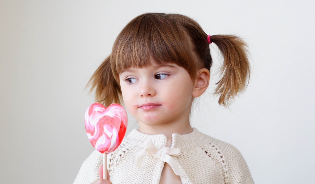 Маленькая девочка с большой конфетой на палочке